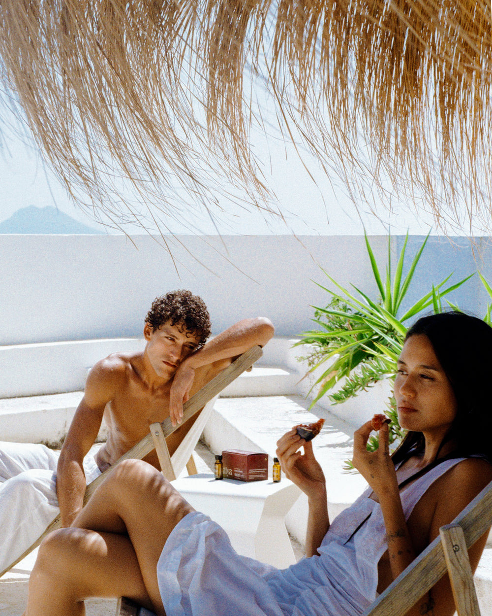 Two people relaxing with Alya olive oil shots by the sea